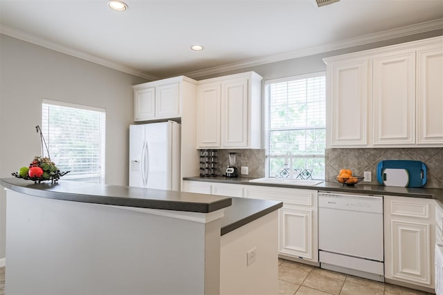 kitchen featuring crown molding, dark countertops, white cabinetry, a sink, and white appliances