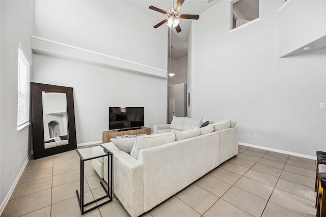 living room featuring light tile patterned floors, ceiling fan, and a high ceiling