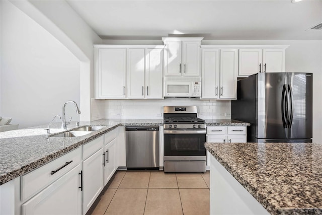 kitchen featuring white cabinetry, appliances with stainless steel finishes, sink, and dark stone countertops