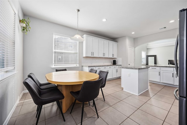 kitchen featuring white cabinetry, light stone countertops, a kitchen island, and pendant lighting