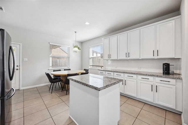 kitchen with light tile patterned flooring, white cabinets, stainless steel refrigerator, and decorative backsplash