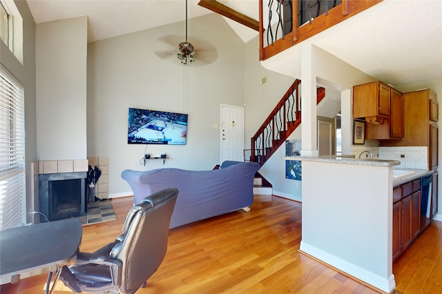 interior space with a fireplace, backsplash, stainless steel dishwasher, light hardwood / wood-style floors, and kitchen peninsula