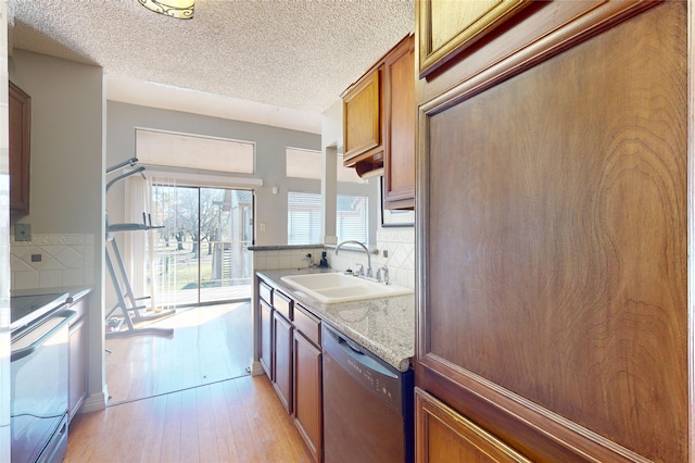 kitchen with light wood-style flooring, electric range oven, brown cabinetry, a sink, and dishwasher