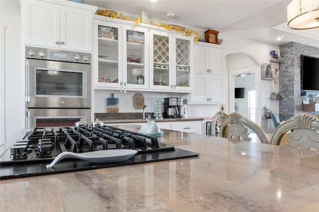 kitchen featuring white cabinetry, gas cooktop, dark stone counters, and stainless steel double oven