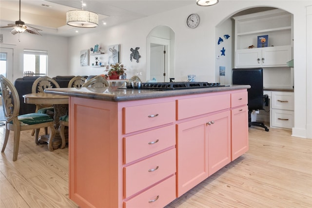 kitchen with light wood-type flooring, a center island, white cabinets, and stainless steel gas cooktop