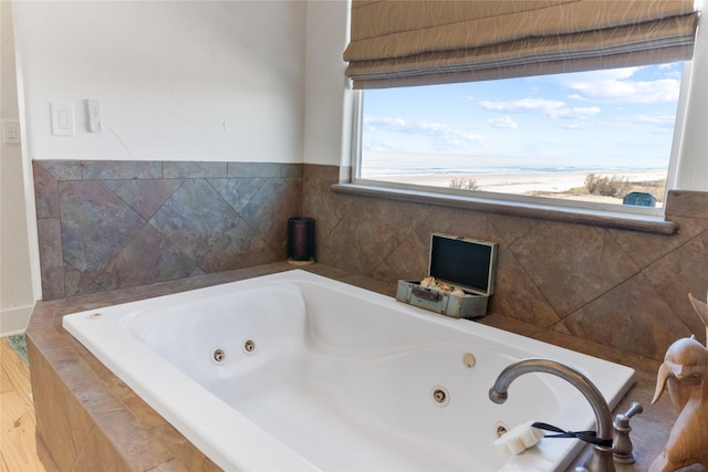 bathroom featuring a relaxing tiled tub and plenty of natural light