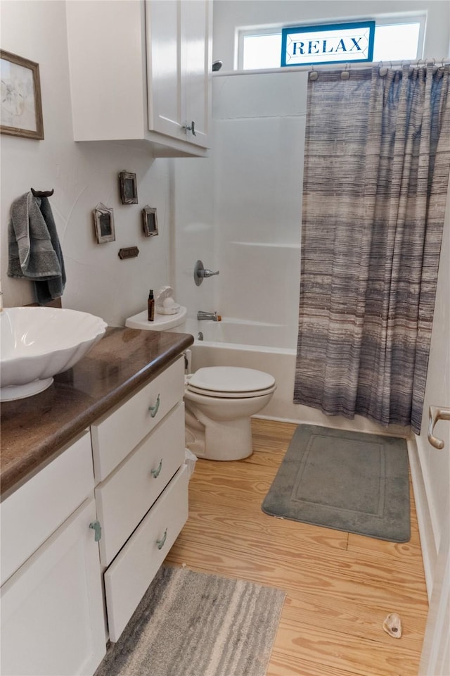 full bathroom with vanity, wood-type flooring, shower / tub combo with curtain, and toilet