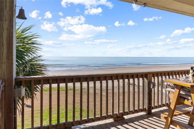 wooden terrace featuring a beach view and a water view