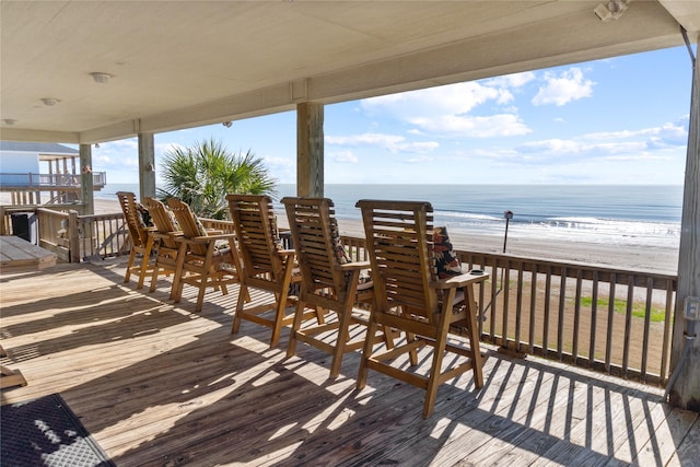 wooden deck featuring a beach view and a water view