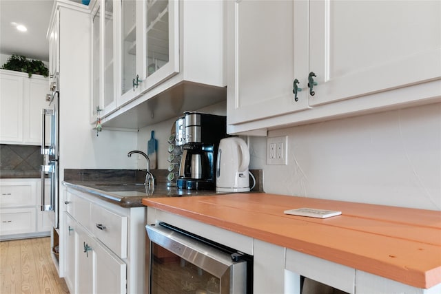 kitchen featuring sink, wooden counters, white cabinetry, backsplash, and wine cooler