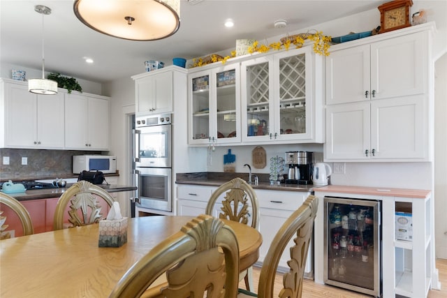 kitchen featuring pendant lighting, stainless steel double oven, white cabinets, and wine cooler