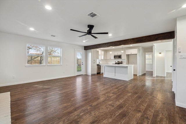 unfurnished living room featuring beamed ceiling, ceiling fan, and dark hardwood / wood-style flooring