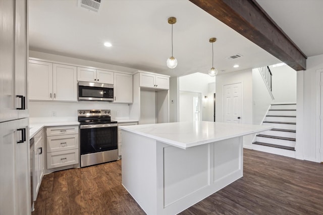 kitchen featuring pendant lighting, white cabinetry, a center island, stainless steel appliances, and beam ceiling