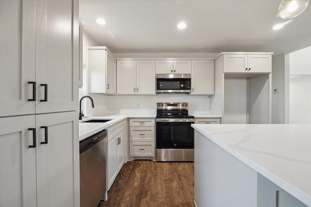 kitchen with sink, stainless steel appliances, dark hardwood / wood-style floors, light stone countertops, and white cabinets