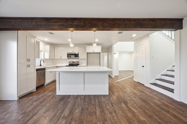 kitchen featuring pendant lighting, appliances with stainless steel finishes, a kitchen island, and white cabinets