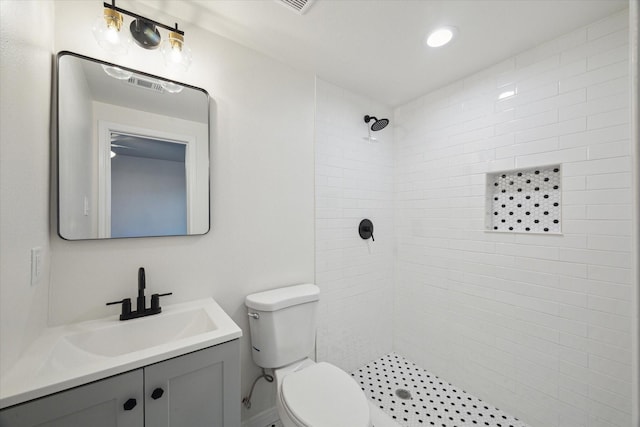 bathroom with vanity, toilet, and tiled shower