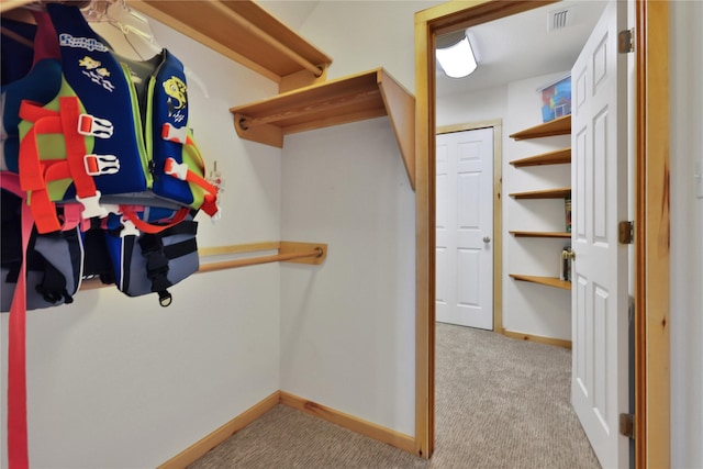 walk in closet featuring light colored carpet