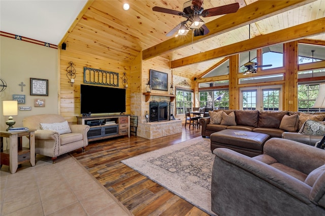 living room featuring a stone fireplace, a wealth of natural light, high vaulted ceiling, and wood walls