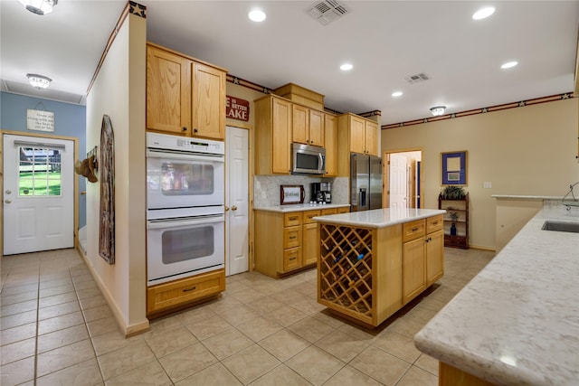 kitchen featuring sink, backsplash, a center island, light tile patterned floors, and stainless steel appliances