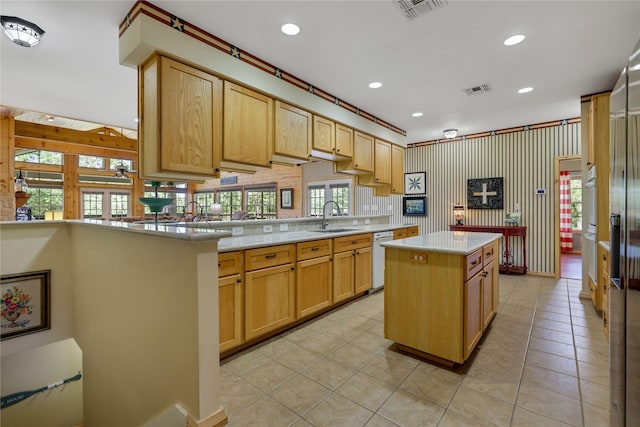 kitchen featuring light tile patterned flooring, sink, light brown cabinets, white dishwasher, and a kitchen island