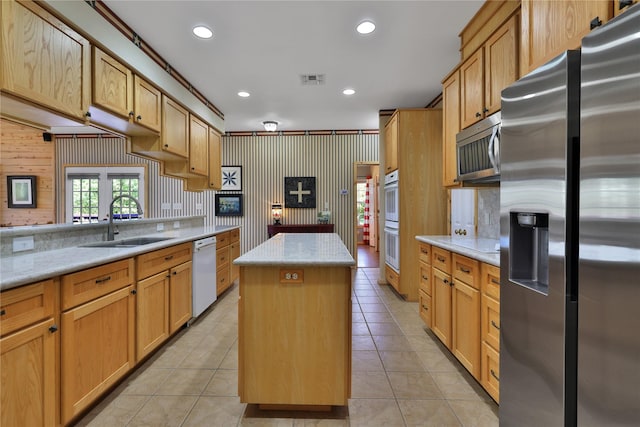 kitchen with stainless steel appliances, sink, a kitchen island, and light tile patterned floors