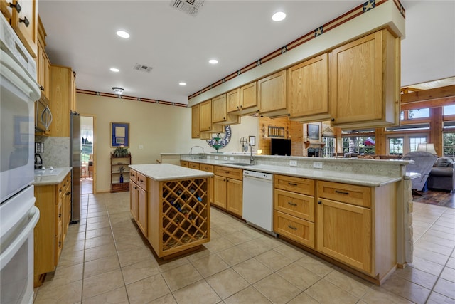 kitchen with light tile patterned flooring, a kitchen island, tasteful backsplash, kitchen peninsula, and white appliances