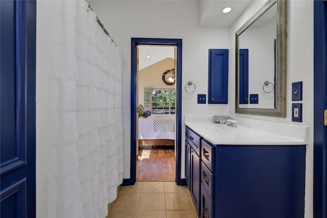 bathroom with tile patterned flooring, vanity, and vaulted ceiling