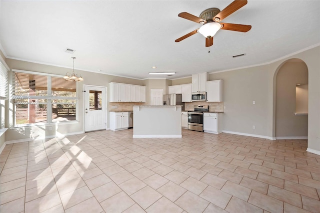 kitchen with hanging light fixtures, stainless steel appliances, tasteful backsplash, ornamental molding, and white cabinets