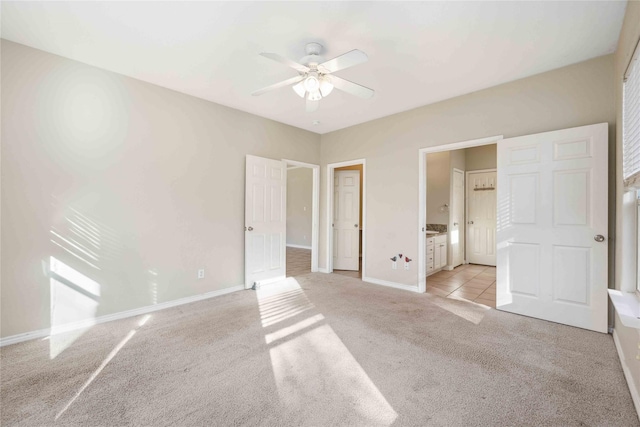 unfurnished bedroom featuring connected bathroom, light colored carpet, and ceiling fan