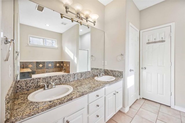 bathroom with a washtub, vanity, and tile patterned floors