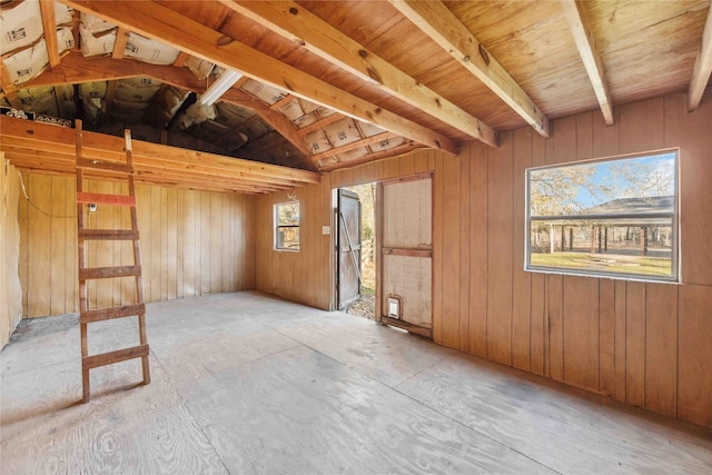 interior space featuring vaulted ceiling and wooden walls