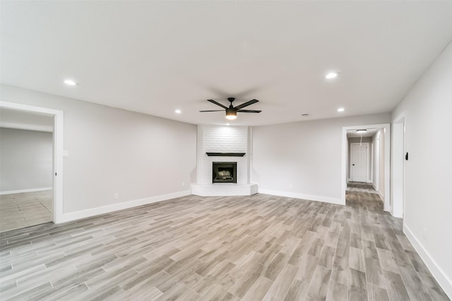 unfurnished living room with a brick fireplace, light hardwood / wood-style floors, and ceiling fan