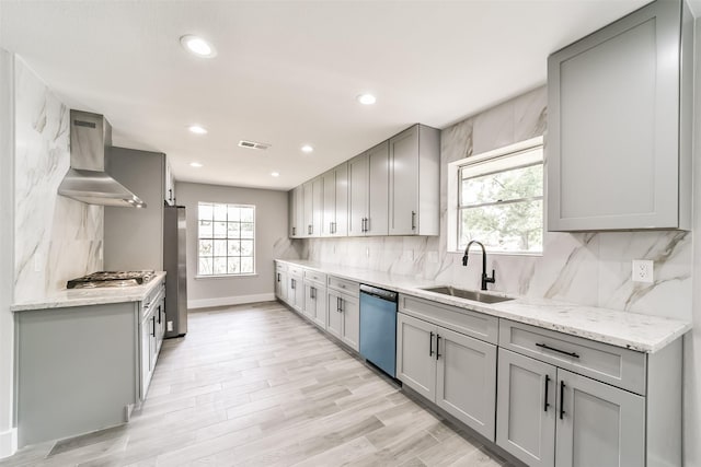 kitchen with stainless steel appliances, gray cabinets, sink, and wall chimney range hood