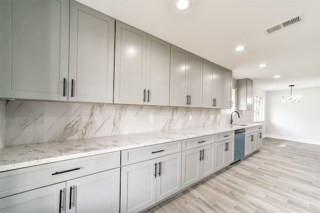 kitchen with sink, dishwasher, tasteful backsplash, light stone counters, and decorative light fixtures