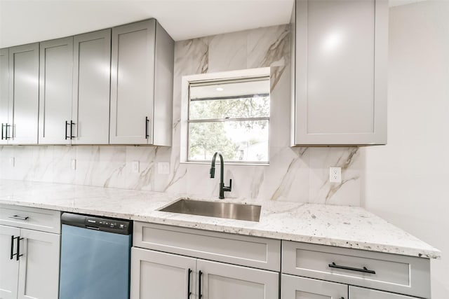 kitchen with sink, gray cabinetry, light stone counters, stainless steel dishwasher, and decorative backsplash