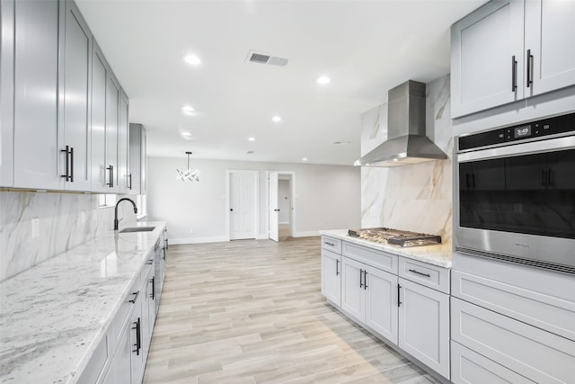 kitchen featuring light stone counters, ventilation hood, and appliances with stainless steel finishes