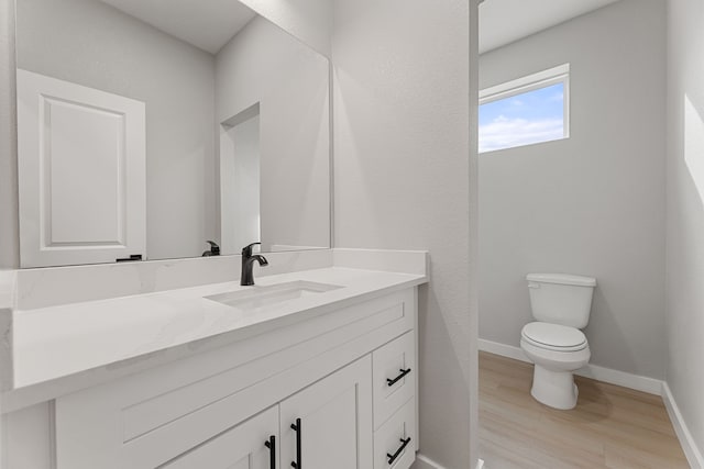 bathroom featuring wood-type flooring, vanity, and toilet