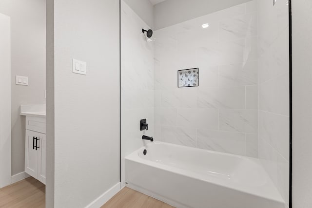 bathroom with tiled shower / bath, hardwood / wood-style floors, and vanity