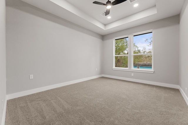 empty room featuring carpet, ceiling fan, and a tray ceiling