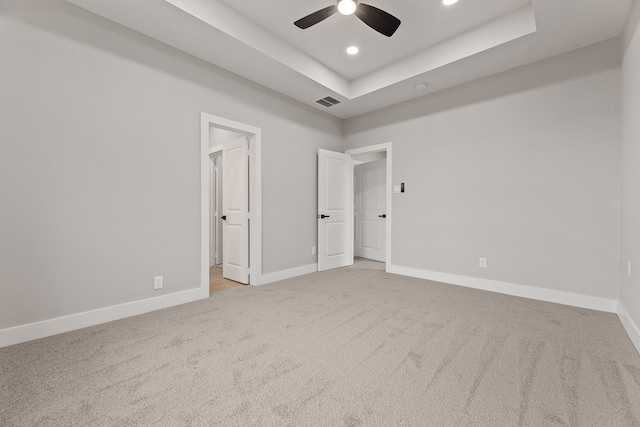 unfurnished bedroom featuring light colored carpet, ceiling fan, and a tray ceiling