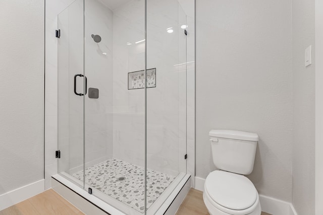 bathroom featuring wood-type flooring, walk in shower, and toilet