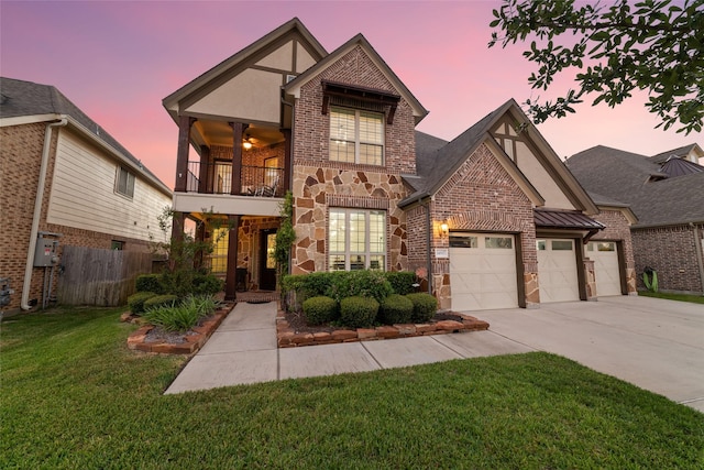 tudor-style house featuring ceiling fan, a yard, and a balcony