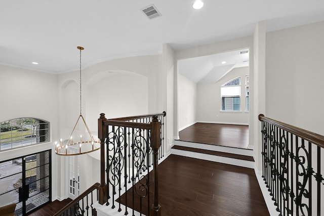 corridor with dark hardwood / wood-style flooring, a chandelier, and vaulted ceiling