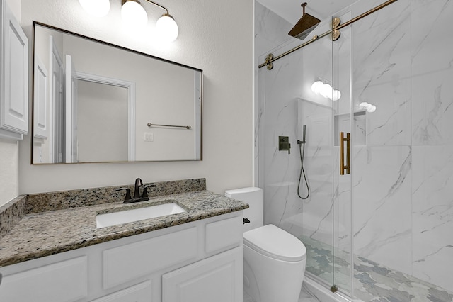 bathroom featuring vanity, a shower with door, and toilet