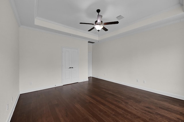 unfurnished room with crown molding, ceiling fan, a tray ceiling, and dark hardwood / wood-style flooring