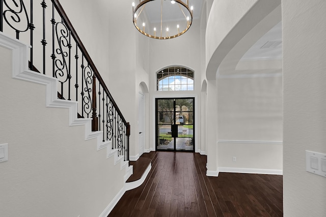 entryway featuring crown molding, dark hardwood / wood-style floors, a chandelier, and a high ceiling