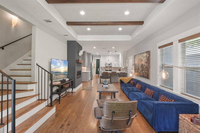 living area featuring light wood-style flooring, recessed lighting, visible vents, stairs, and beam ceiling