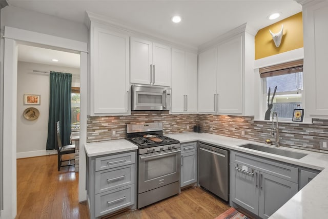 kitchen featuring appliances with stainless steel finishes, wood finished floors, a sink, and gray cabinetry