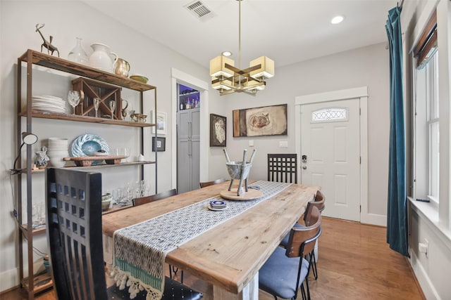 dining space featuring baseboards, visible vents, wood finished floors, an inviting chandelier, and recessed lighting