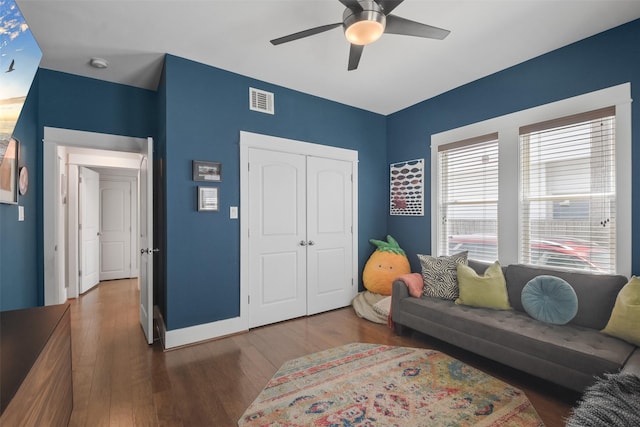 living area featuring dark wood-style flooring, visible vents, ceiling fan, and baseboards